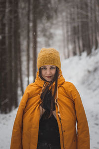 Portrait of smiling woman standing in snow during winter