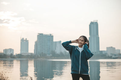 Woman standing by buildings in city against sky