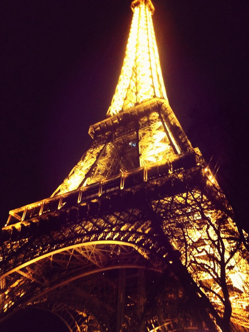illuminated, night, low angle view, architecture, built structure, famous place, building exterior, international landmark, travel destinations, tower, tall - high, capital cities, tourism, travel, city, sky, eiffel tower, yellow, clear sky, no people