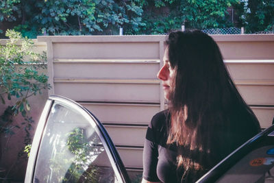 Thoughtful young woman looking away by car