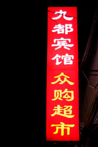 Low angle view of illuminated lantern sign against black background