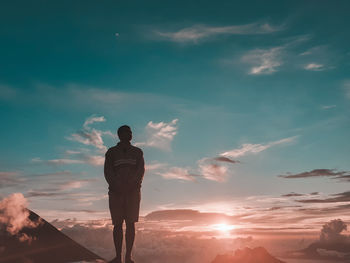 Rear view of silhouette man standing against sky during sunset