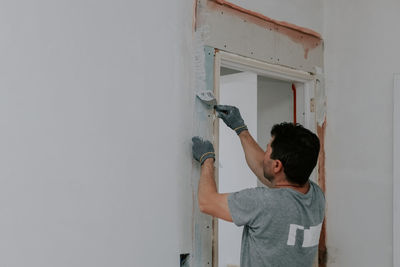 One young man covers up the mesh in the doorway with putty.