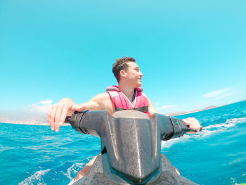 Portrait of young woman standing against sea