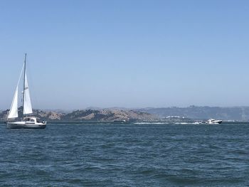 Sailboats sailing on sea against clear blue sky