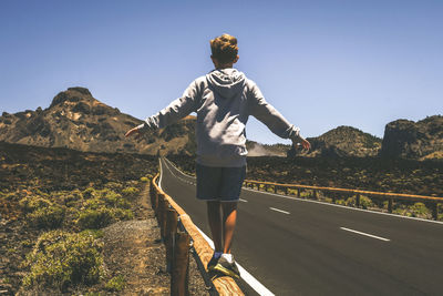 Rear view of man on road against sky