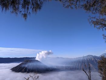 Smoke emitting from volcanic mountain against blue sky