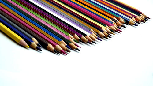 High angle view of colored pencils on white background