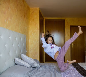 Portrait of girl jumping on bed at home