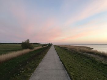 Empty road along calm sea at sunset