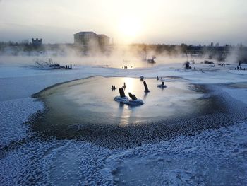 People on frozen water against sky