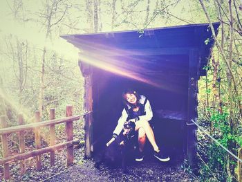 Portrait of young woman standing on tree trunk