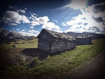 House on field against cloudy sky