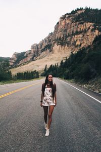 Woman walking on road against mountains