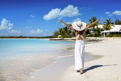 Rear view of woman standing by sea against sky