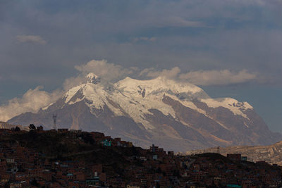 Scenic view of town by mountains against sky