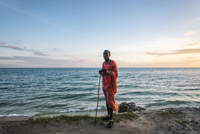 Man standing on beach against sky during sunset