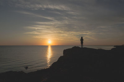 Silhouette man standing on beach against sky during sunset