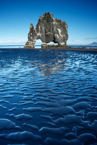 Rock formation at beach against blue sky