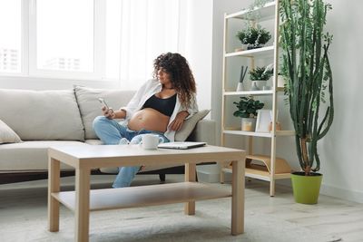 Side view of woman sitting on sofa at home