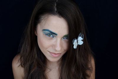 Close-up portrait of young woman with make-up against white background