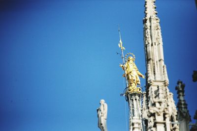 Low angle view of statue of building against blue sky