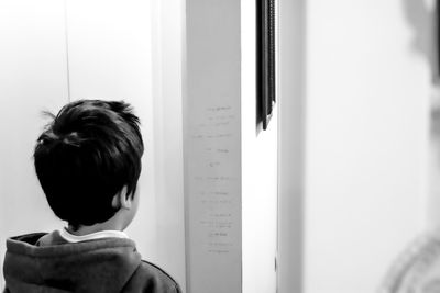 Rear view of boy reading text written on wall