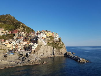 Townscape by sea against clear blue sky