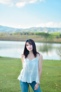 Young woman standing against lake