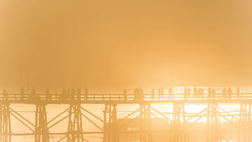 Silhouette people walking on mon bridge at sangkhla buri district against sky