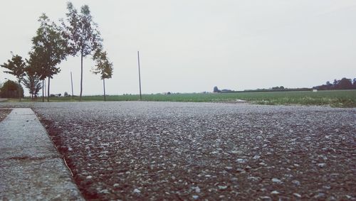 Road amidst field against clear sky