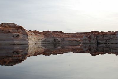 Reflection of rocks in water against sky