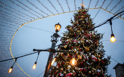 Low angle view of illuminated christmas tree against sky at dusk