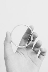 Close-up of hand holding ring against white background