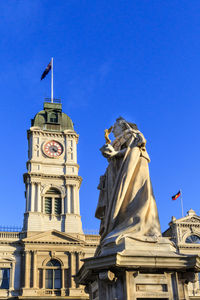 Low angle view of statue of building against blue sky