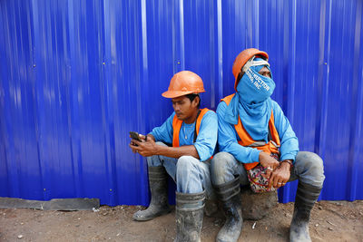 Full length of man holding blue while sitting outdoors