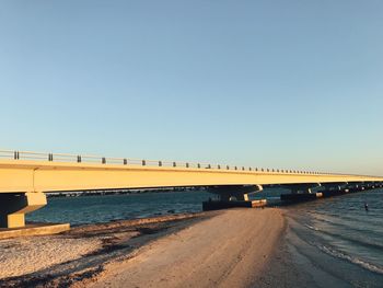 Bridge over sea against clear blue sky
