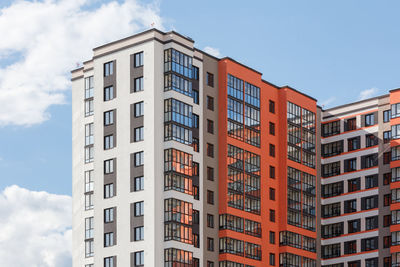 New high apartament building with multiple balcony and windows on blue sky with white clouds 