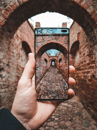 Midsection of person holding umbrella against built structure