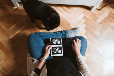 Woman holding photograph while sitting on hardwood floor