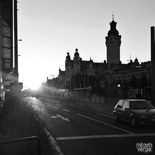 transportation, architecture, clear sky, car, built structure, building exterior, land vehicle, road, mode of transport, street, copy space, city, road marking, travel, sunlight, outdoors, the way forward, travel destinations, no people, day