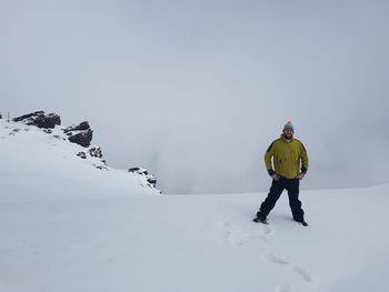 Man standing on snow covered mountain against sky