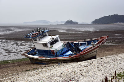 Boats moored on beach against clear sky