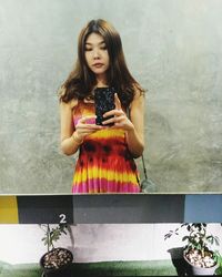 Young woman looking at camera while standing in mirror