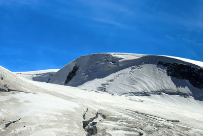 Snow covered mountain against blue sky