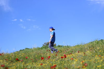 Rear view of boy walking on field against sky