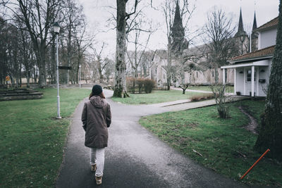 Rear view of man on street amidst trees and plants