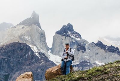 Portrait of female hiker sitting on rock against mountains at torres del paine national park
