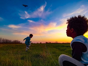 Full length of friends on field against sky during sunset