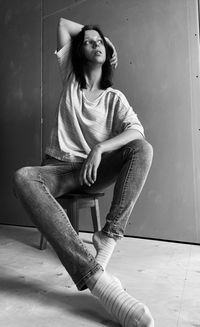 Portrait of young woman sitting on wall at home